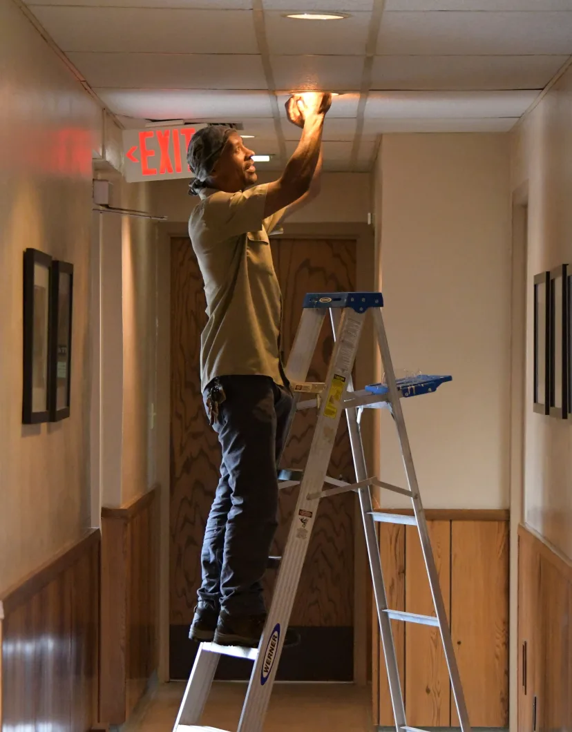 Tony standing on a ladder and fixing a lightbulb
